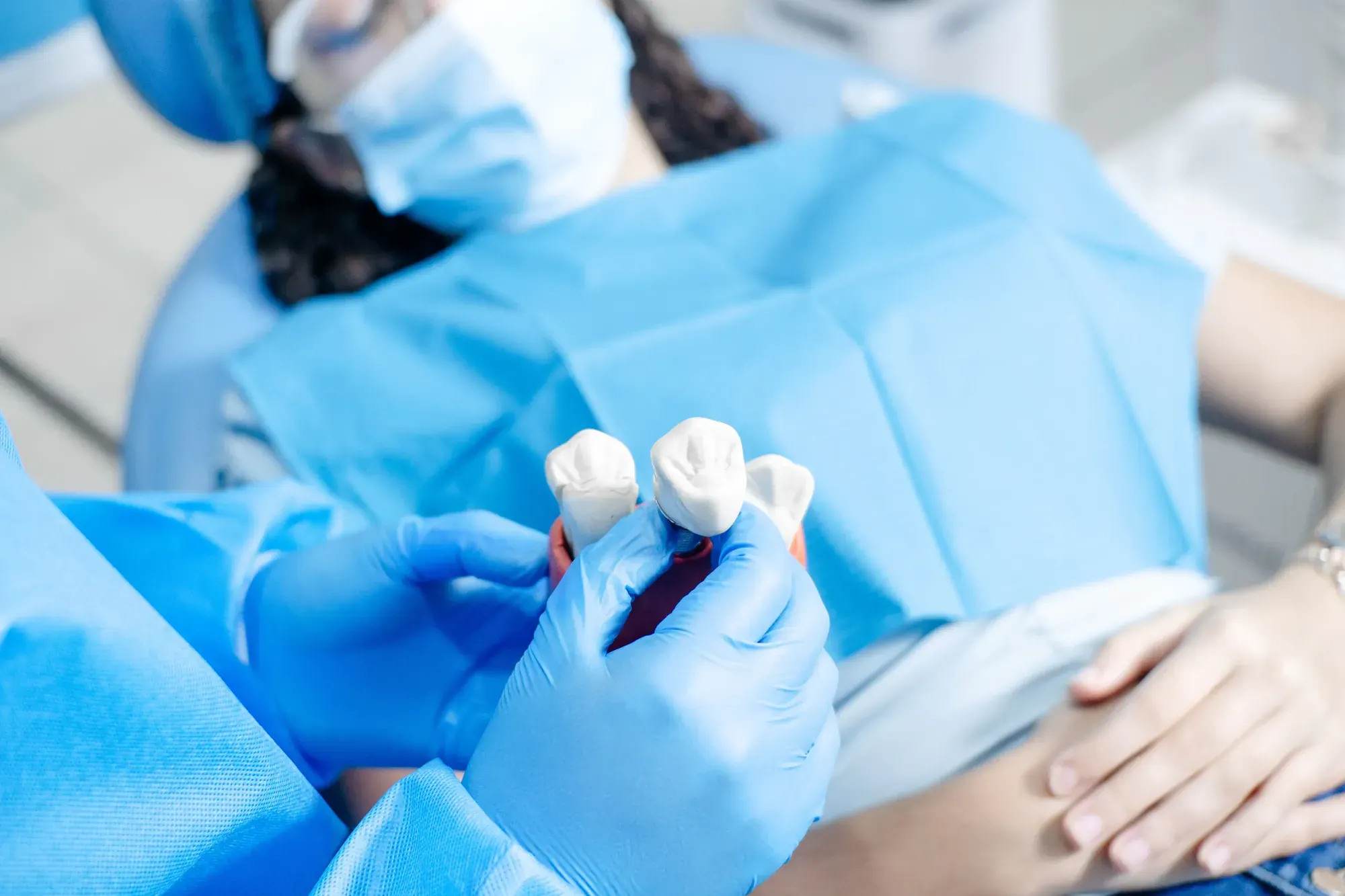 Dental professional using a tooth model to explain porcelain inlays and onlays to a patient
