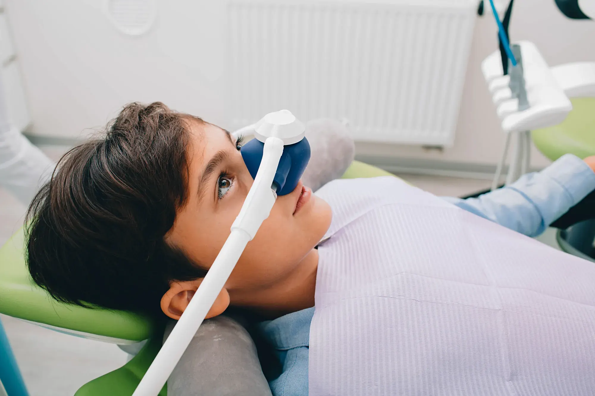 Calm young patient breathing nitrous oxide through a nasal mask for comfortable sedation dentistry