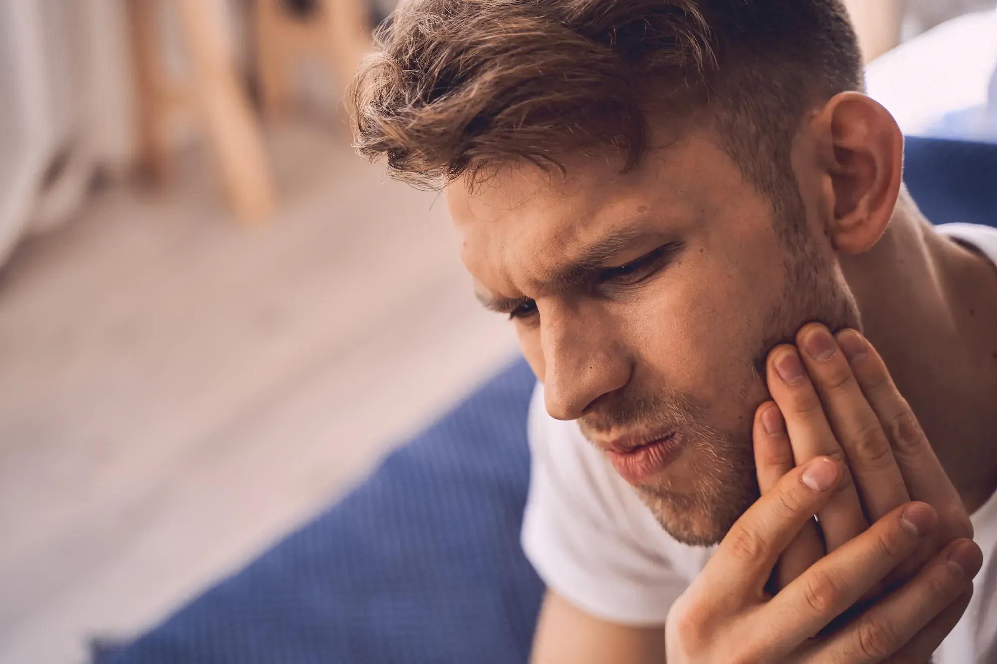 Man holding his jaw in pain from a toothache, needing a same-day emergency dentist in Tribeca